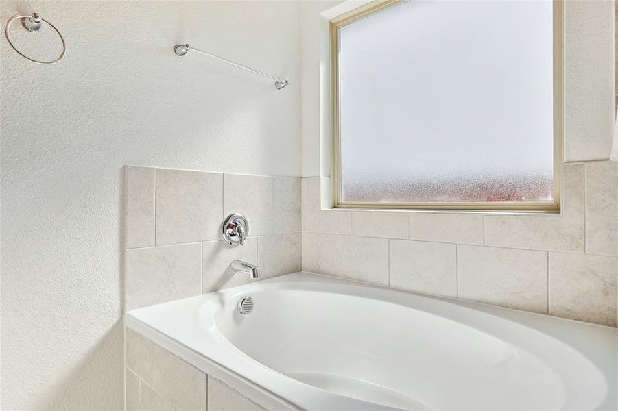 Bathroom with tiled tub and a healthy amount of sunlight