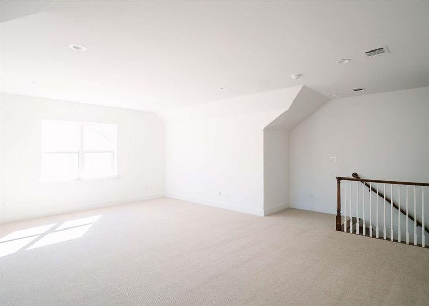 Additional living space with lofted ceiling and light colored carpet