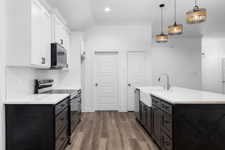 Kitchen featuring appliances with stainless steel finishes, decorative light fixtures, crown molding, white cabinets, and vaulted ceiling