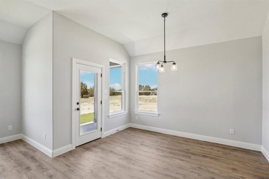 Unfurnished dining area with lofted ceiling, hardwood / wood-style floors, and an inviting chandelier