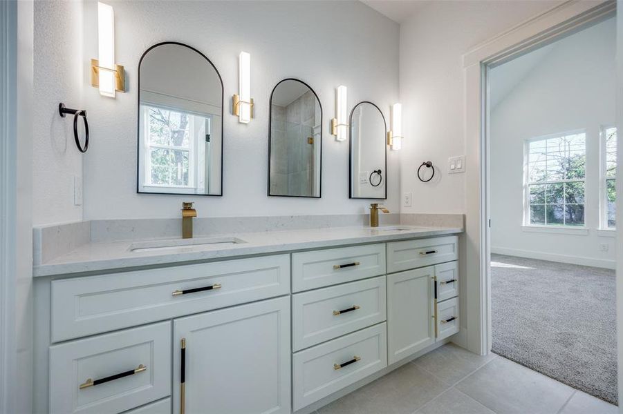 Bathroom featuring vanity, vaulted ceiling, a healthy amount of sunlight, and tile patterned flooring