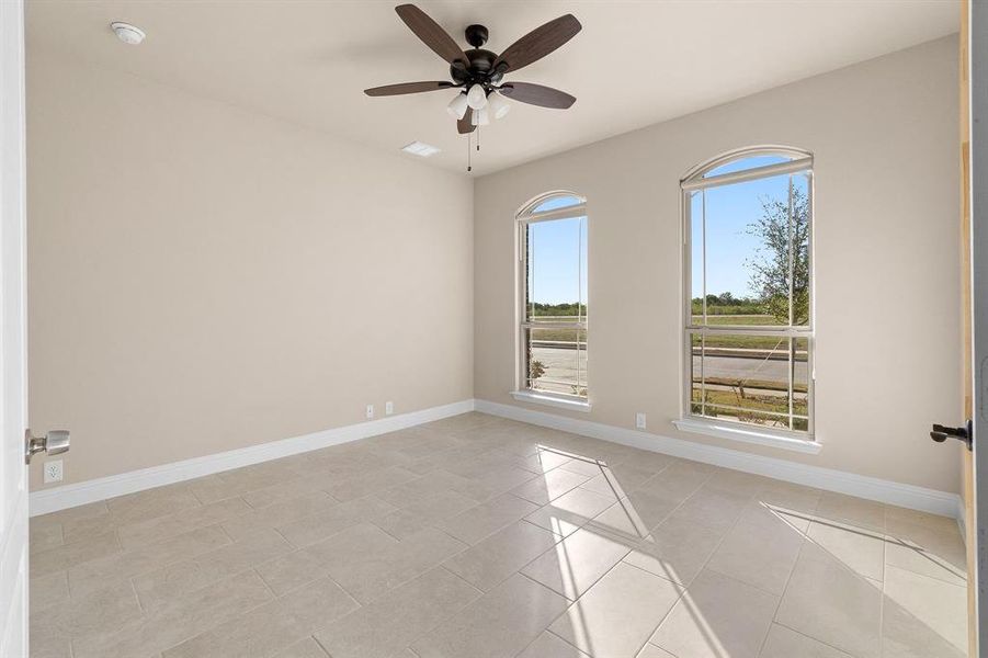 Empty room with a wealth of natural light, light tile patterned floors, and ceiling fan