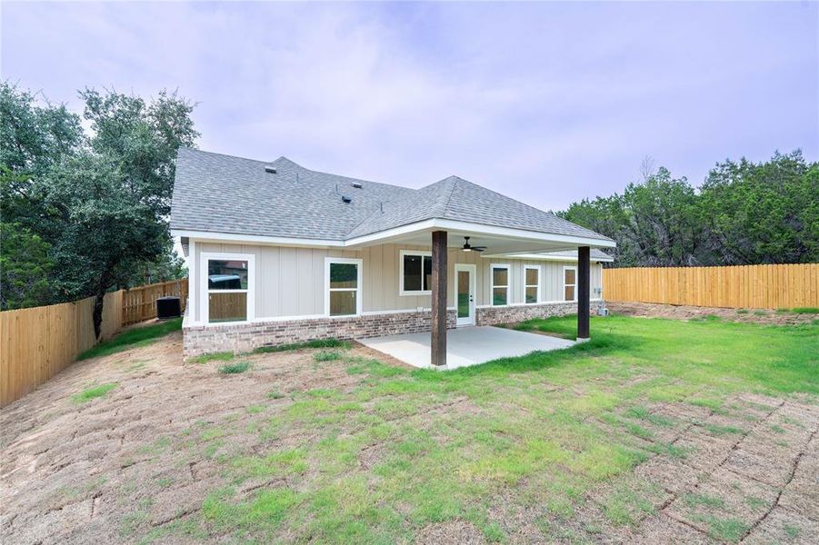 Back of house with ceiling fan, a lawn, and a patio