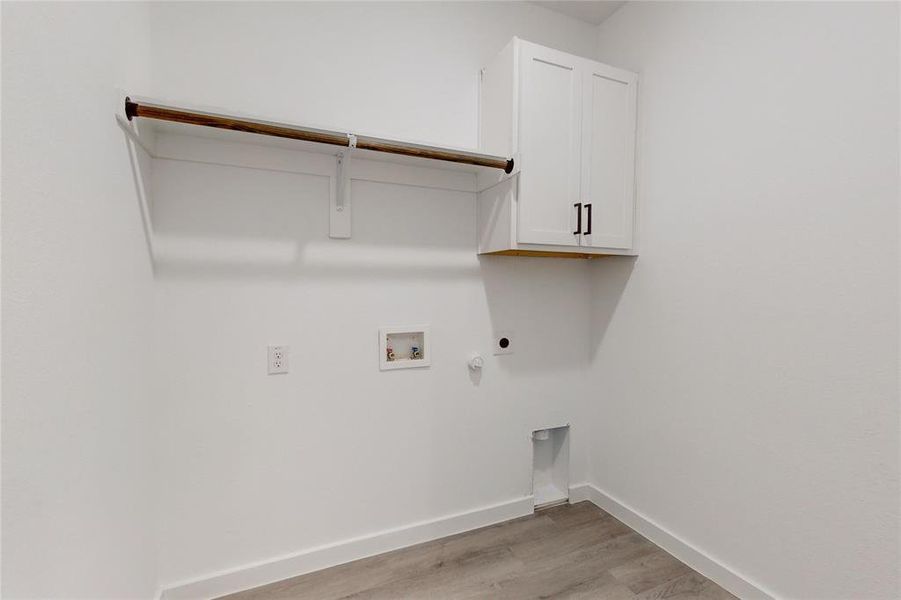 Washroom featuring light wood-type flooring, hookup for a gas dryer, hookup for an electric dryer, washer hookup, and cabinets