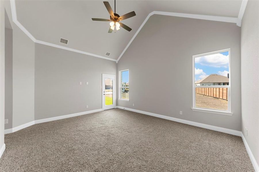 Spare room with ceiling fan, high vaulted ceiling, and carpet