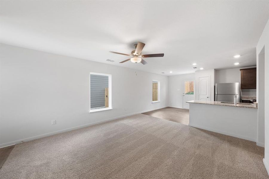 Living room with ceiling fan and light colored carpet