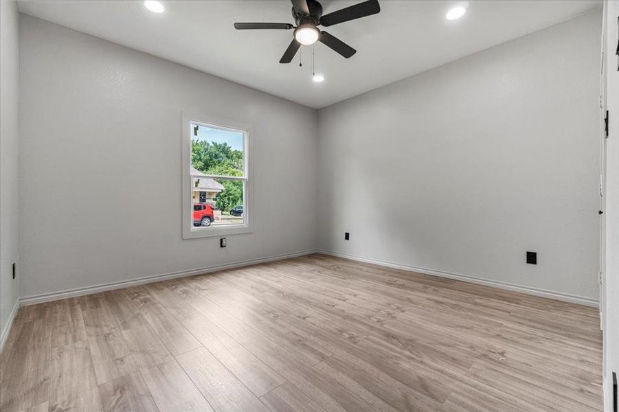 Empty room with ceiling fan and light wood-type flooring