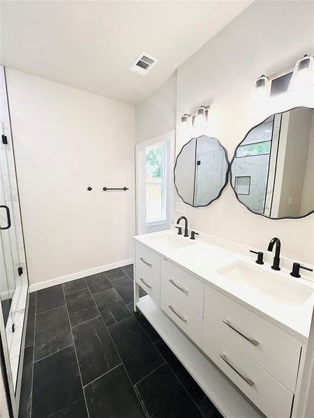 Bathroom featuring tile patterned flooring, dual vanity, and an enclosed shower