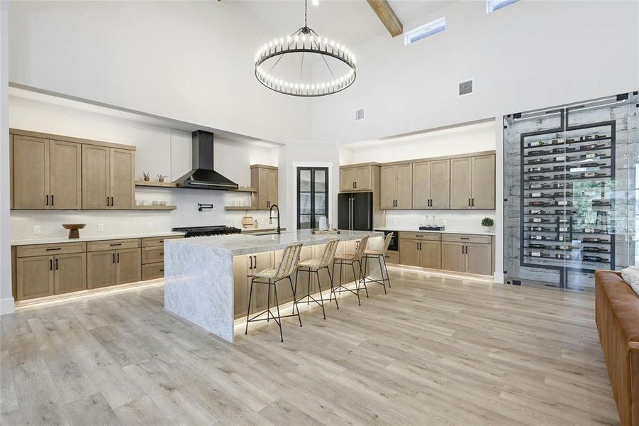 A chef’s dream kitchen featuring abundant custom KraftMade cabinets, massive center island, quartz countertops, black stainless appliances, pot filler, 48in gas range, and oversized walk-in pantry.