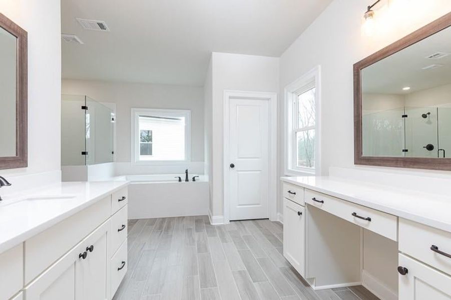 Owner's Bathroom featuring a healthy amount of sunlight, shower with separate bathtub, and vanity. Photo not actual home, but previously built Mansfield plan.