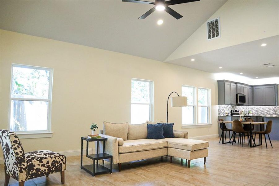 Living room with light hardwood / wood-style flooring, high vaulted ceiling, and ceiling fan