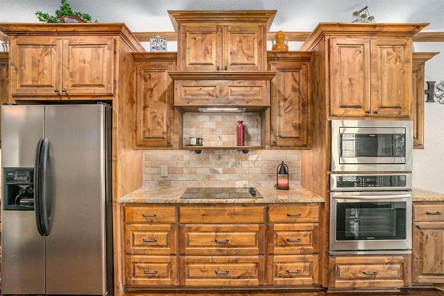 Kitchen with tasteful backsplash, stainless steel appliances, and light stone counters