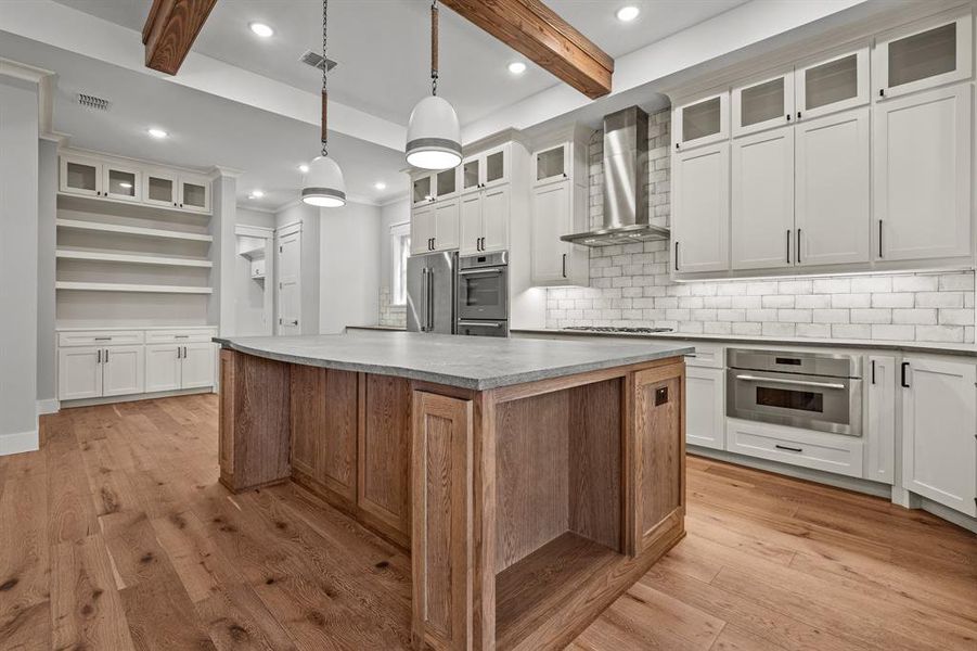 Kitchen with wall chimney exhaust hood and white cabinetry