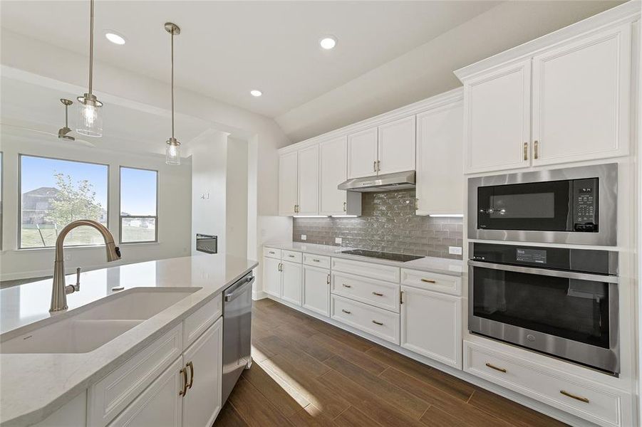 Kitchen featuring pendant lighting, wood-style flooring, composition sink, white cabinets, and SS appliances