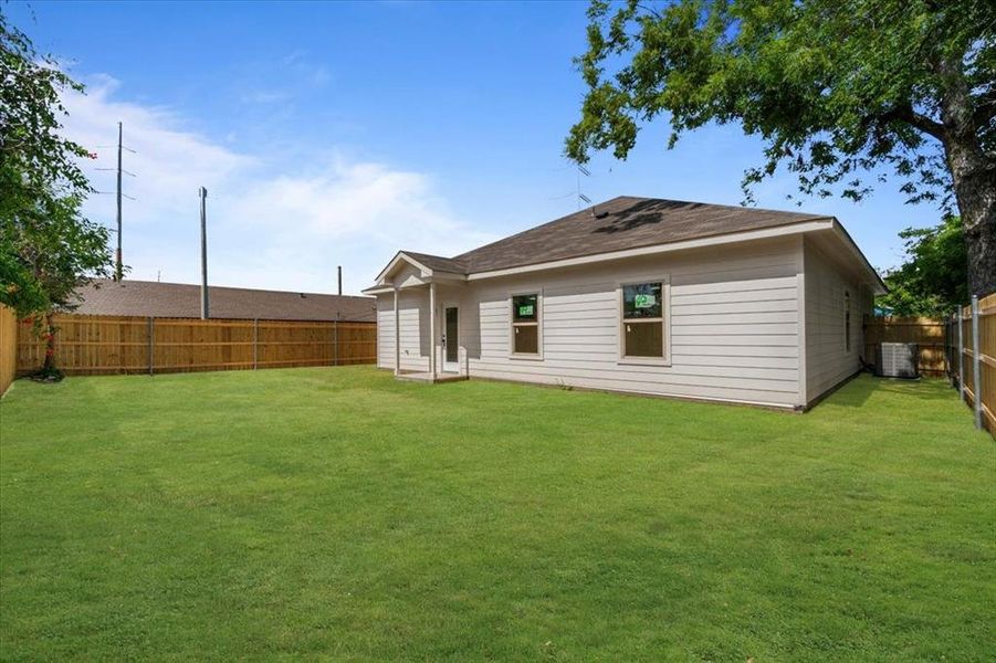 Back of property featuring central AC and a yard