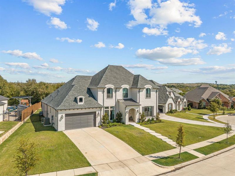 French country inspired facade featuring a front yard, central AC unit, and a garage