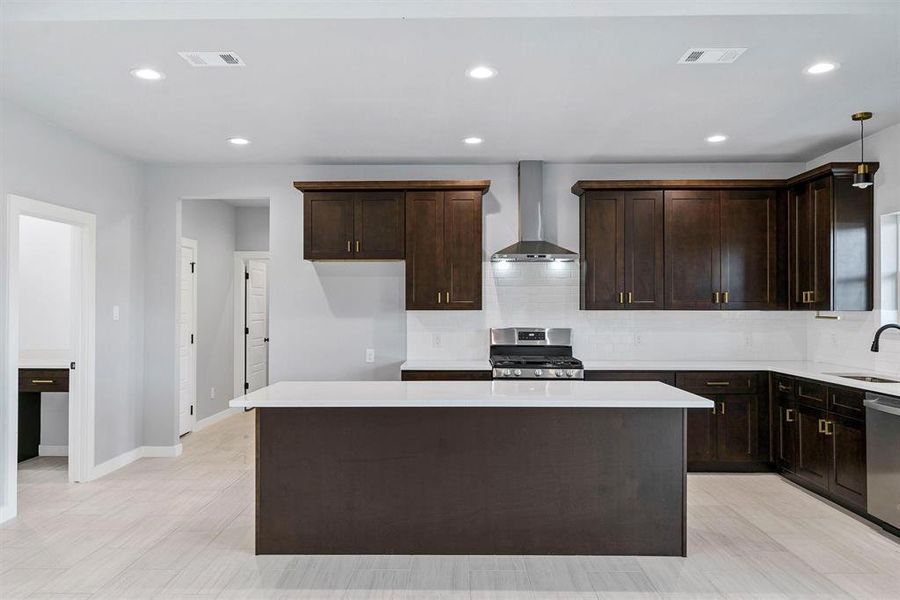 Kitchen featuring sink, wall chimney exhaust hood, stainless steel appliances, and a kitchen island