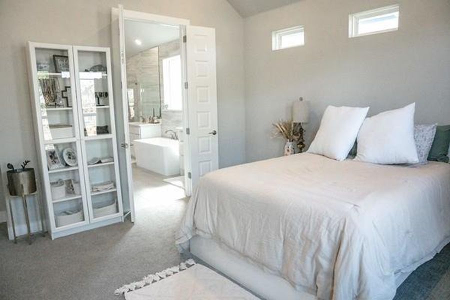 Carpeted bedroom with lofted ceiling and ensuite bath