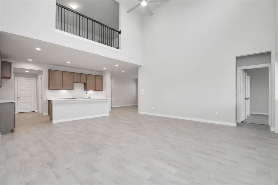 Welcome family and guests to your charming living room! With its high ceilings, recessed lighting, ceiling fan, custom paint, beautiful flooring, and large windows that let in abundant natural light, this room is perfect for gatherings.