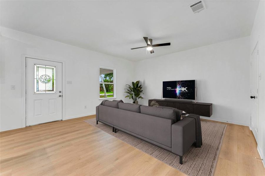 The living room exudes a sense of spaciousness and elegance, with the front door and window inviting natural light to flow freely. (Virtual Staging May Be Present)