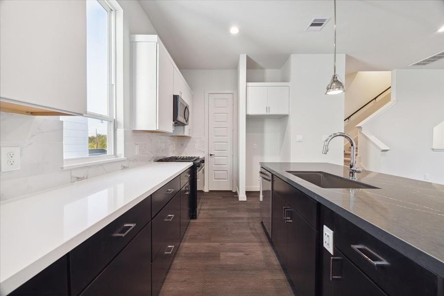 The clean lines of the cabinetry, paired with high-end stainless steel appliances and a pristine marble-patterned backsplash, create a luxurious yet practical kitchen environment. With plenty of counter space and storage, this kitchen is designed for both functionality and elegance.