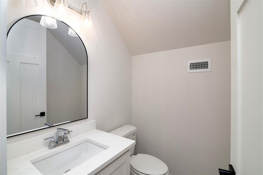 Bathroom with vanity, toilet, and vaulted ceiling