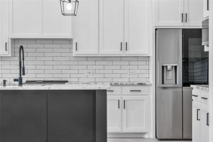 Kitchen with white cabinets, light stone countertops, stainless steel refrigerator with ice dispenser, and tasteful backsplash