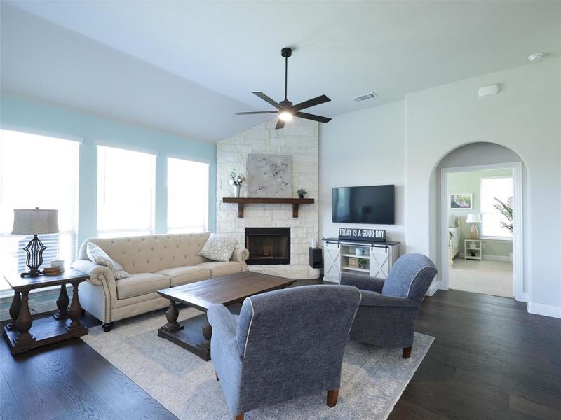 Living room with a fireplace, vaulted ceiling, dark hardwood / wood-style floors, and ceiling fan