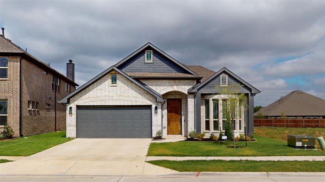 View of front of property featuring a garage and a front lawn