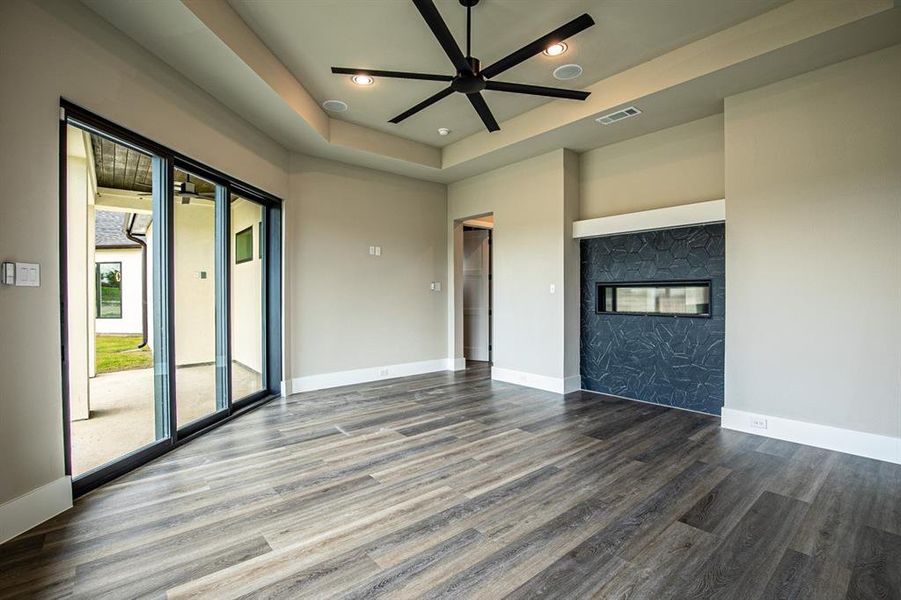 Unfurnished living room featuring a tray ceiling, wood-type flooring, and ceiling fan