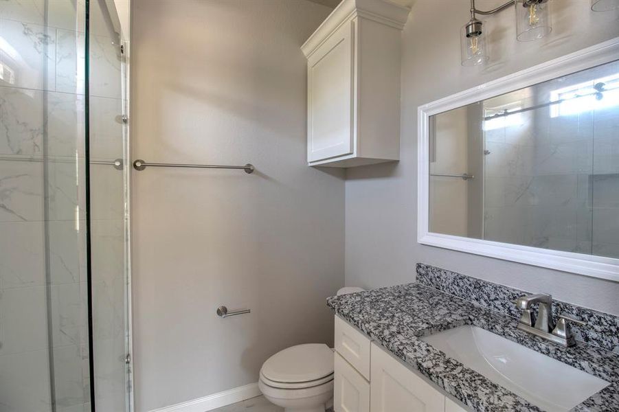 Bathroom with a shower with shower door, toilet, and vanity