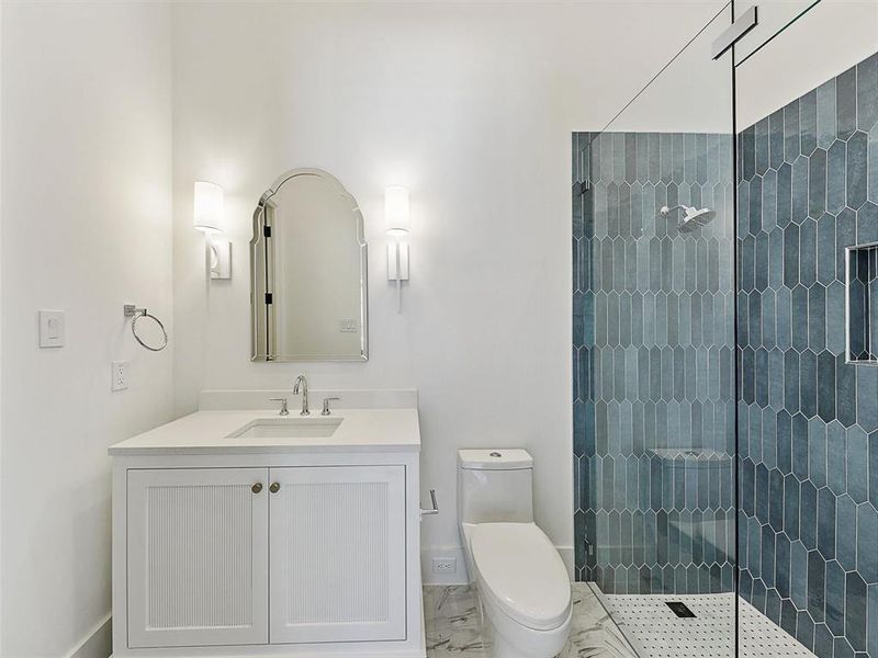 Bathroom with vanity, toilet, and tiled shower