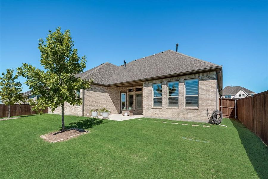 Back of house with ceiling fan, a yard, and a patio