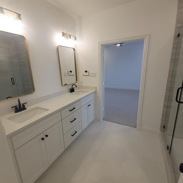 Bathroom featuring tile floors, a shower with door, large vanity, and double sink