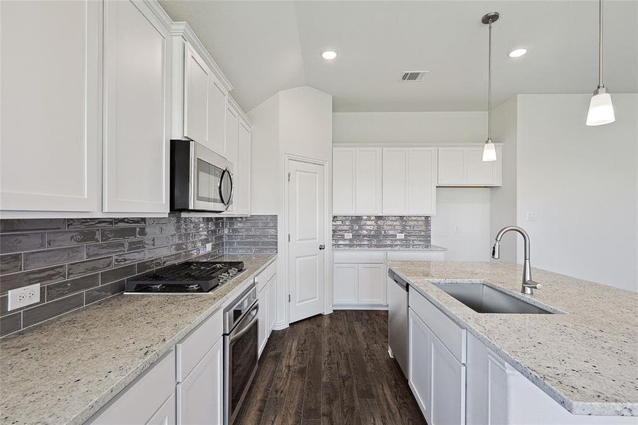 Kitchen featuring dark hardwood / wood-style floors, tasteful backsplash, white cabinets, sink, and appliances with stainless steel finishes