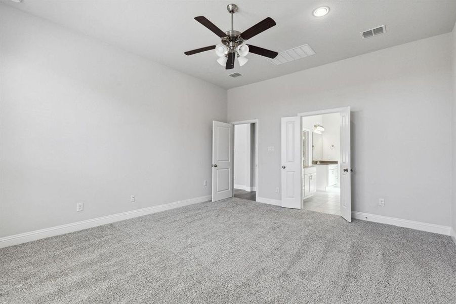 Unfurnished bedroom with ensuite bath, ceiling fan, and light colored carpet