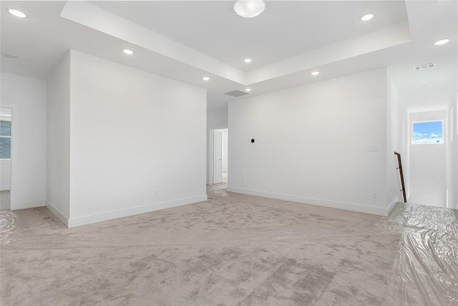 Empty room with light colored carpet and a tray ceiling