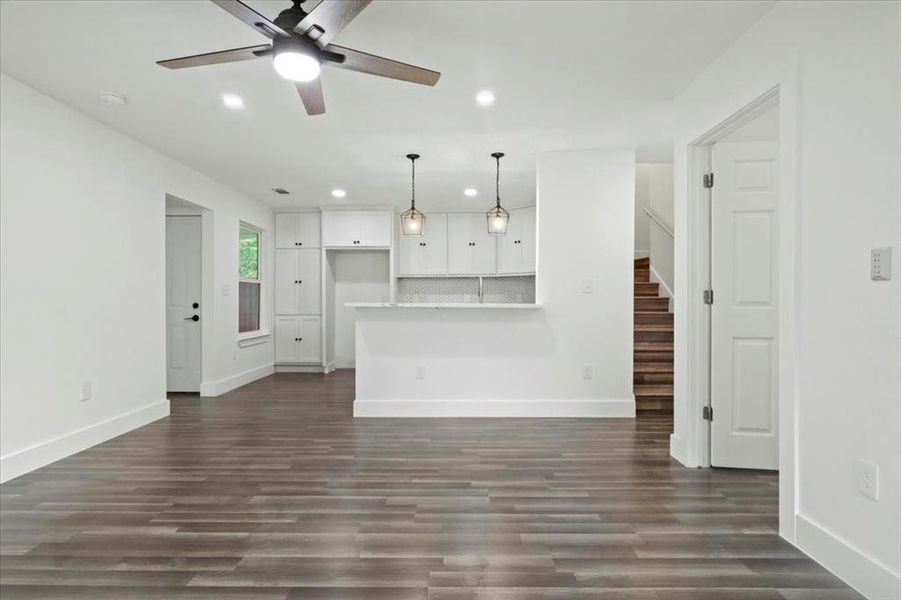 Unfurnished living room featuring ceiling fan and dark hardwood / wood-style flooring