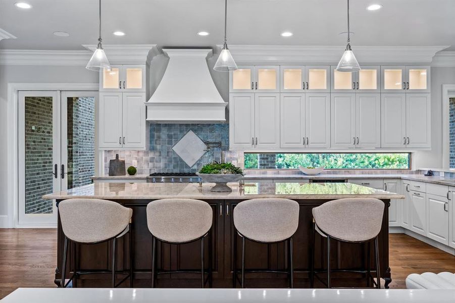 Kitchen with pendant lighting, a center island, custom exhaust hood, and white cabinets