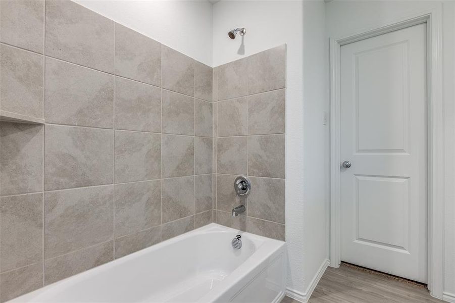 Bathroom with hardwood / wood-style flooring and tiled shower / bath combo