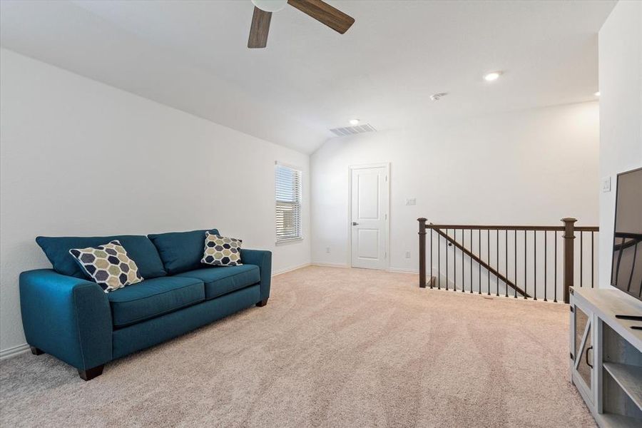 Sitting room with ceiling fan, lofted ceiling, and light colored carpet