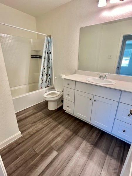 Full bathroom featuring toilet, hardwood / wood-style floors, vanity, and shower / tub combo with curtain