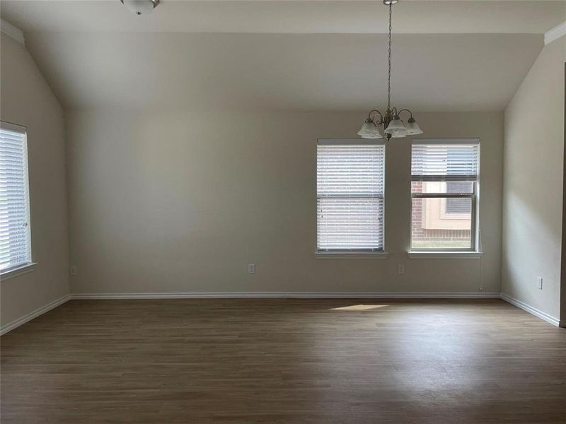 Unfurnished room featuring a wealth of natural light, a chandelier, dark hardwood / wood-style flooring, and lofted ceiling