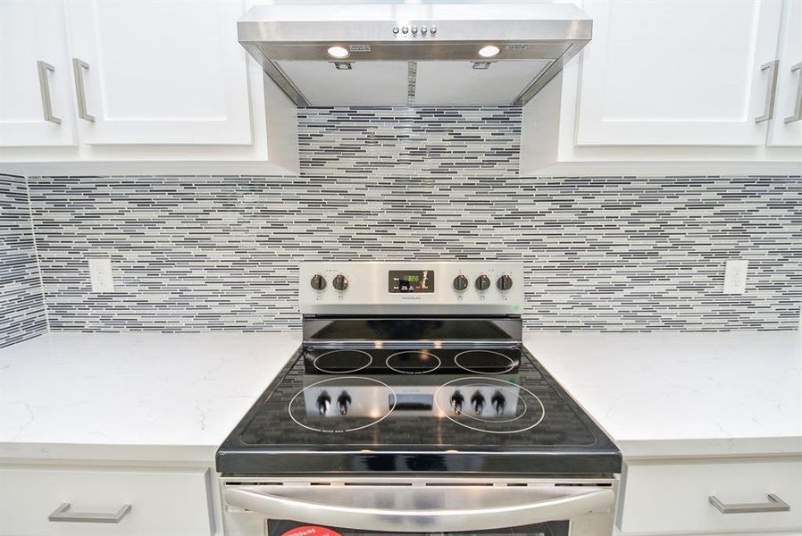 Gas cooktop with a vented hood and a single oven, complemented by a beautiful tile backsplash.