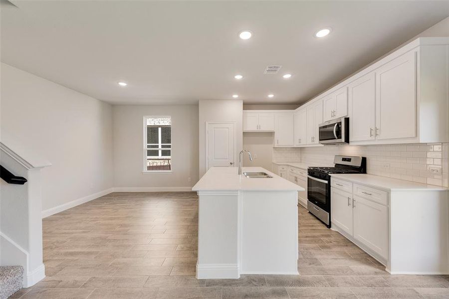 Kitchen featuring white cabinets, a center island with sink, appliances with stainless steel finishes, and sink