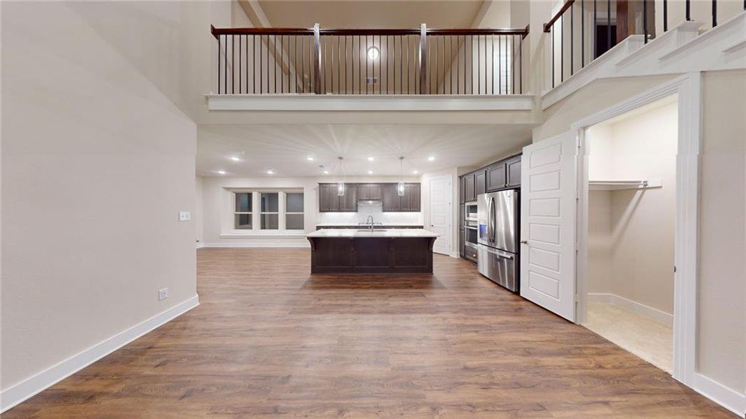 Kitchen featuring hardwood / wood-style flooring, stainless steel fridge with ice dispenser, an island with sink, and a high ceiling