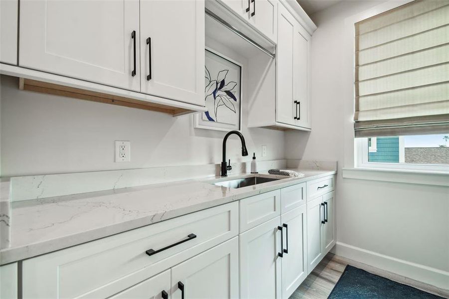 Large laundry room with sink and storage cabinets.
