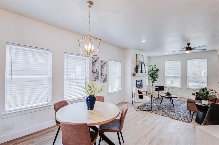 Dining area with light wood-type flooring and ceiling fan with notable chandelier