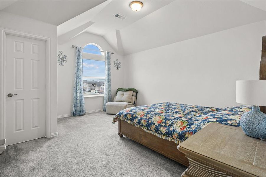 Bedroom featuring light carpet and lofted ceiling