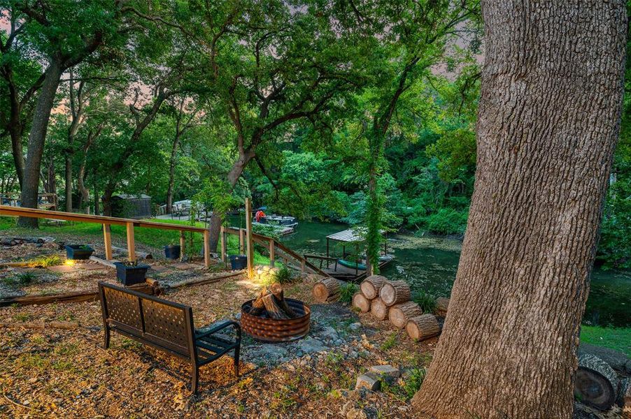 View of back yard featuring an outdoor fire pit with view of the water and private boat dock